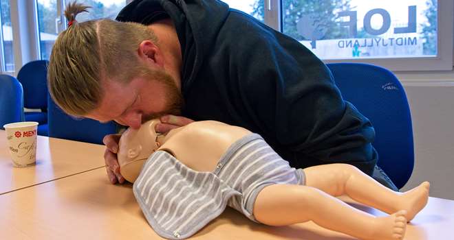 Førstehjælp baby far øver indblæsning.jpg