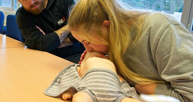 Førstehjælp baby mor øver indblæsning far kigger.jpg